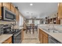 Bright kitchen and dining area featuring wood cabinets, stainless steel appliances, and views to the living area at 15470 W Mauna Loa Ln, Surprise, AZ 85379