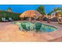 Lush backyard featuring a sparkling pool, charming tiki umbrella and comfortable lounge chairs, perfect for relaxation at 16375 W Cortez St, Surprise, AZ 85388