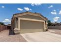 Side view of a tan home showing the 2-car garage and spacious driveway on a sunny day, surrounded by gravel at 1680 E Cardinal Dr, Casa Grande, AZ 85122
