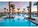 Community pool surrounded by palm trees with lounge chairs for residents to enjoy the sunset at 23139 E Lords Way, Queen Creek, AZ 85142