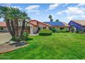 Inviting single-story home featuring a lush lawn, mature palm trees, and solar panels at 5710 E Anderson Dr, Scottsdale, AZ 85254