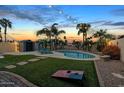 Inviting backyard oasis featuring a sparkling pool, lush lawn, and mature palm trees at 7140 E Juanita Ave, Mesa, AZ 85209