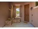 Covered front porch featuring desert themed decor, stacked stone accents and modern steel front door at 1225 S 160Th Ln, Goodyear, AZ 85338