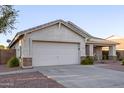 Image focuses on the side of a house and the garage, showcasing the desert landscaping and concrete driveway at 12374 W Hopi St, Avondale, AZ 85323