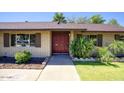 Inviting home facade featuring a brick exterior, red double doors, and mature landscaping at 3009 W Christy Dr, Phoenix, AZ 85029