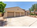Spacious three-car garage attached to a desert-style home with ample driveway space at 915 W Orchard Ln, Litchfield Park, AZ 85340