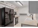 Functional kitchen features modern black appliances, white cabinetry, and neutral countertops at 9929 W Thunderbird Blvd, Sun City, AZ 85351