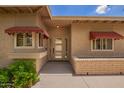 Home front entrance with an attractive door, awnings, brick siding, and well-maintained landscaping at 10318 E Michigan Ave, Sun Lakes, AZ 85248