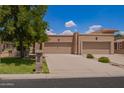 Traditional desert home boasts a two-car garage, lush lawn and xeriscaping, under a beautiful blue sky at 10318 E Michigan Ave, Sun Lakes, AZ 85248