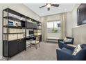 Well-lit home office with custom shelving, desk, comfortable chairs, and large window at 14825 W Whitehorn Way, Surprise, AZ 85387