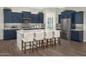 Modern kitchen with dark blue cabinets, stainless steel appliances, and a large center island with seating at 14825 W Whitehorn Way, Surprise, AZ 85387