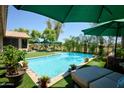 Backyard pool features blue water, poolside furniture, lush landscaping and covered umbrellas on the artificial grass at 22364 N 59Th Ln, Glendale, AZ 85310
