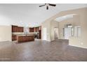 Open concept kitchen with island featuring dark wood cabinets, tile flooring, and seamless flow into the living area at 2620 E Rustling Oaks Ln, Phoenix, AZ 85024