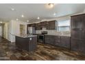 A modern kitchen is spacious and features an island, stainless steel appliances, and wood-look flooring at 5601 W Missouri Ave # 150, Glendale, AZ 85301