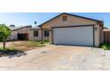 A single-story home with an attached garage, concrete driveway, and low maintenance yard with a small tree at 8051 W Mariposa Dr, Phoenix, AZ 85033