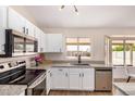 Bright kitchen featuring white cabinets, stainless steel appliances, and a large window overlooking the backyard at 8103 E Dartmouth St, Mesa, AZ 85207