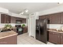 Charming kitchen with tile flooring, black appliances, dark wood cabinets, and modern refrigerator at 9649 S 51 St St, Phoenix, AZ 85044