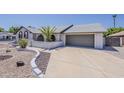 View of the home showing the front yard with desert landscaping and attached garage at 2307 W Nido Ave, Mesa, AZ 85202