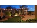 Outdoor space offers a water feature, lush green grass, and ambient string lights for evening enjoyment at 2413 W Kachina Trl, Phoenix, AZ 85041