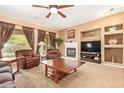 Cozy living room featuring carpet, armchairs, a fireplace, a ceiling fan, and lots of natural light at 2413 W Kachina Trl, Phoenix, AZ 85041