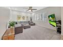 Cozy carpeted living room with a comfortable sectional, bright window shutters, and a mounted TV at 306 E Sarah Ln, Tempe, AZ 85284