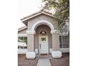 Charming front entrance features a white door with glass panes, framed by an arched entryway with tan pillars and an overhead light fixture at 3446 N Ravine --, Mesa, AZ 85215