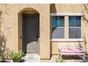 Close-up of a home's inviting front door and porch area, complete with bench and potted plants at 451 S Hawes Rd # 53, Mesa, AZ 85208