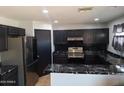 Modern kitchen featuring black cabinets, stainless steel appliances, and striking black marble countertops at 7224 W Pioneer St, Phoenix, AZ 85043