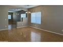 Open-concept living room with hardwood floors, large windows, and an archway leading to the dining area at 11921 W Madison St, Avondale, AZ 85323