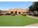 Tan home features a two-car garage, desert landscaping, and green lawn at 2229 S 82Nd Ln, Phoenix, AZ 85043