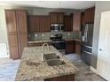 Modern kitchen with stainless steel appliances, granite countertops, and stylish dark wood cabinets at 38242 N Armadillo Dr, San Tan Valley, AZ 85140
