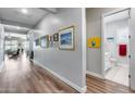 Well-lit hallway featuring wood flooring and decorative art leading to an open living space and bathroom at 1202 E Nolan Pl, Chandler, AZ 85249