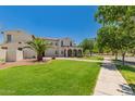 Spacious two-story home with a well-maintained lawn, mature trees, and a circular driveway, offering curb appeal and ample parking at 20409 W Thayer St, Buckeye, AZ 85396