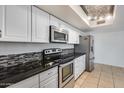 Updated kitchen with stainless steel appliances, white cabinets, tile backsplash, and dark granite countertops at 3251 W Mercer Ln, Phoenix, AZ 85029