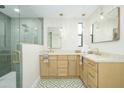 Stylish bathroom showcasing double vanities, brass fixtures, decorative floor tiles, and a glass shower enclosure at 5937 E Corrine Dr, Scottsdale, AZ 85254