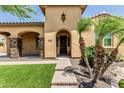 Close up of a home with stone pillars and a dark wood front door and manicured front lawn at 7242 W Rowel Rd, Peoria, AZ 85383
