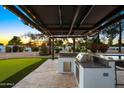 Outdoor stainless steel grill under a lighted pergola, next to a putting green at 13620 N 80Th Pl, Scottsdale, AZ 85260
