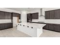 Modern kitchen featuring a large center island, dark wood cabinetry, and stainless steel appliances at 20256 W Monterey Way, Buckeye, AZ 85396