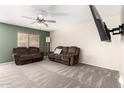 Inviting living room featuring neutral carpet, fan, and a mounted television for entertainment at 3049 W Santa Cruz Ave, San Tan Valley, AZ 85144