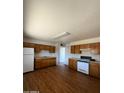 Functional kitchen featuring wood cabinets, white appliances, and laminate flooring at 3441 W Windrose Dr, Phoenix, AZ 85029