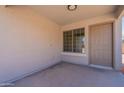 Enclosed front porch of a home with a window, beige walls, and a neutral-colored front door at 37053 W Amalfi Ave, Maricopa, AZ 85138