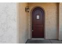 Close up of the rich wood front door with sidelight, decorative sconce and textured stucco wall at 16846 N 49Th Way, Scottsdale, AZ 85254