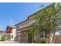 Two-story home featuring neutral stucco, brown trim, brick accents, and a two-car garage, surrounded by lush landscaping at 1879 W 23Rd Ave, Apache Junction, AZ 85120