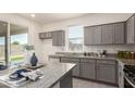 Modern kitchen featuring granite countertops, stainless appliances, gray cabinets, and natural light at 1879 W 23Rd Ave, Apache Junction, AZ 85120