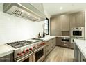 Gourmet kitchen showcasing a professional-grade range, custom hood, and subway tile backsplash at 2315 E Mine Creek Rd, Phoenix, AZ 85024