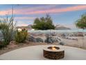 Outdoor living space showcasing a fire pit and a unique desert mural on the back wall at 2487 S Conestoga Rd, Apache Junction, AZ 85119