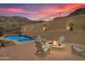 Beautiful backyard with a pool, fire pit, and chairs, set against the backdrop of a desert mountain at 2722 W Hiddenview Dr, Phoenix, AZ 85045