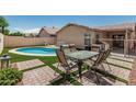 Inviting backyard featuring a sparkling pool, outdoor dining set, and well-maintained artificial turf at 2813 N 107Th Dr, Avondale, AZ 85392