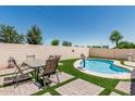 Inviting pool area with a patio table set, synthetic grass, and privacy wall creating a perfect backyard oasis at 2813 N 107Th Dr, Avondale, AZ 85392