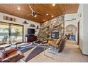 Comfortable living room featuring a stone fireplace, wood ceiling and backyard view at 3357 N Ashbrook E St, Mesa, AZ 85213